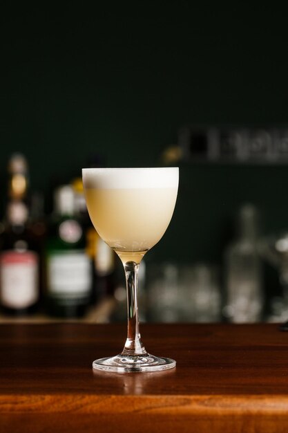 Whisky cocktail pisco sour avec sirop de sucre blanc d'oeuf de citron vert en verre sur fond flou foncé Espace pour le texte