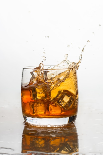 Whisky avec glace dans un verre avec des éclaboussures