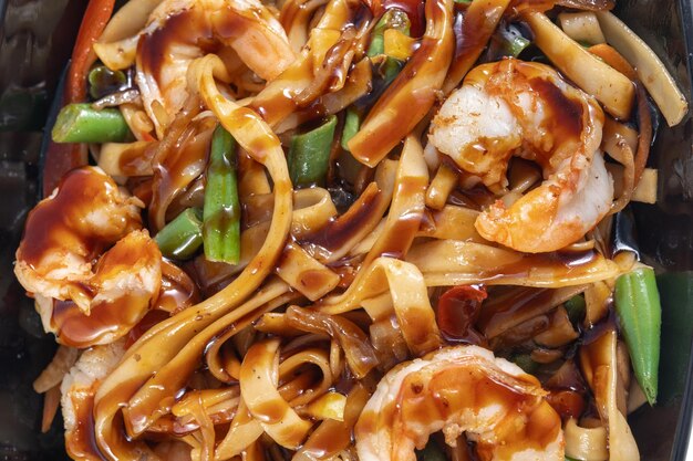 Wok aux crevettes dans une belle assiette noire Clouseup vue de dessus