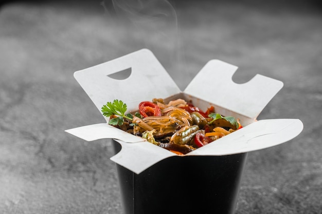 Wok en boîte de nouilles de riz dans un récipient alimentaire noir