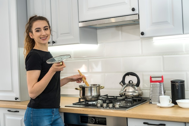 Woman cooking food on kitchen avec poêle à frire sur plaque