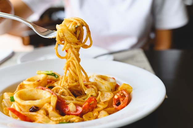 Woman eating spaghetti sauce blanche aux fruits de mer avec une fourchette au restaurant italien. Concept de nourriture et de cuisine.