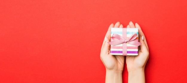 Woman hold boîte-cadeau de Noël sur fond coloré