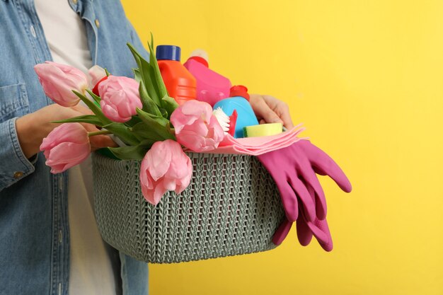 Woman hold panier avec des outils de nettoyage sur jaune