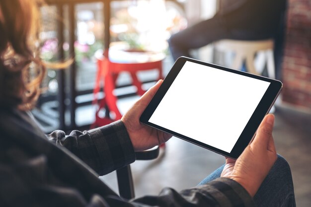 Woman holding black tablet pc avec écran vide horizontalement dans cafe