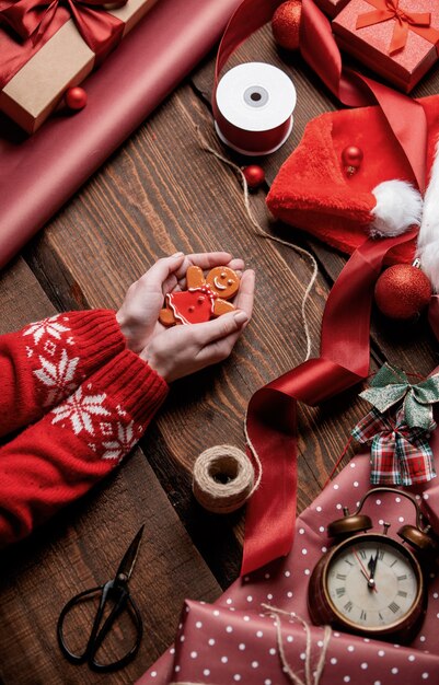 Woman holding gingerbread man cookie sur table en bois dans le temps d'emballage