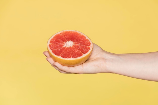 Woman holding pamplemousse sur un fond jaune