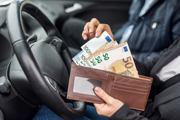 Woman holding wallet avec euro assis dans la voiture