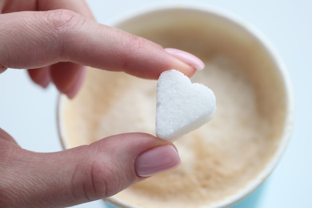 Photo woman putting cube de sucre de café en forme de coeur gros plan