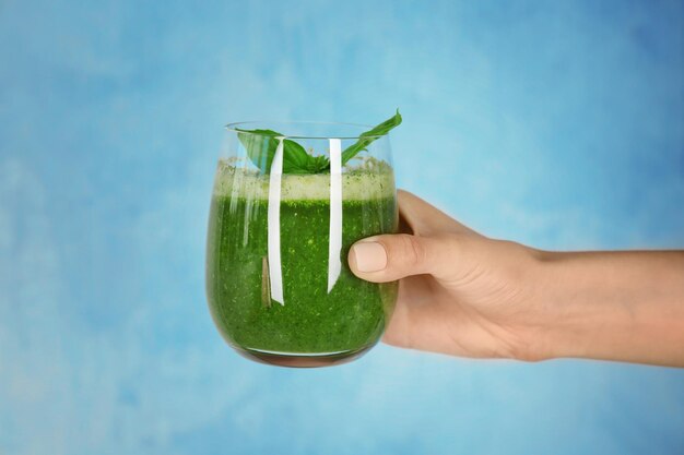 Woman's hand holding glass avec smoothie vert sur fond clair