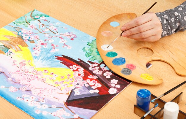 Woman's hand painting paysage japonais à l'intérieur sur la table en bois avec pinceau et palette Artiste dans son atelier