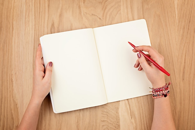 Woman's hands holding journal personnel pour la conception sur un mur de bureau en bois, plat poser