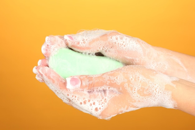 Photo woman's hands in soapsuds sur fond orange gros plan