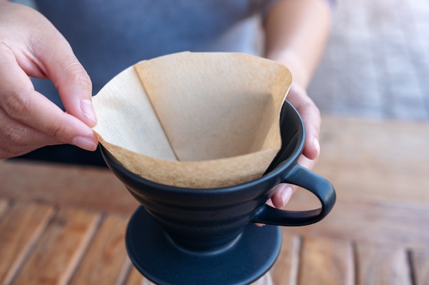 Woman's hands réglage d'un filtre pour faire un café goutte à goutte sur une table en bois vintage