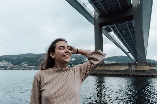 Woman smiling tout en regardant loin de la caméra avec copie espace sous un pont, mer relax concepts