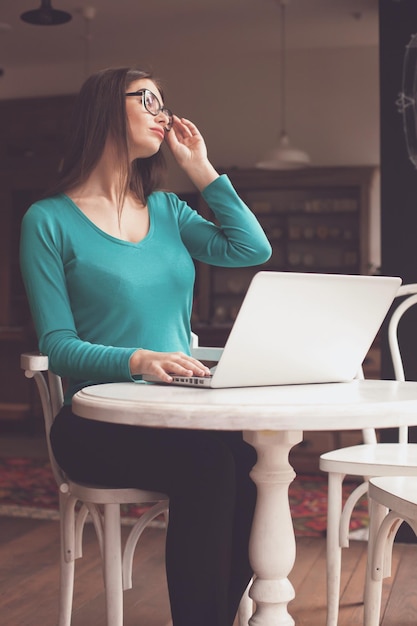 Womanfreelancer regarde par la fenêtre à la table blanche