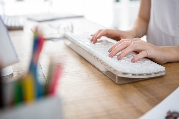 Womans mains tapant sur un clavier dans un bureau