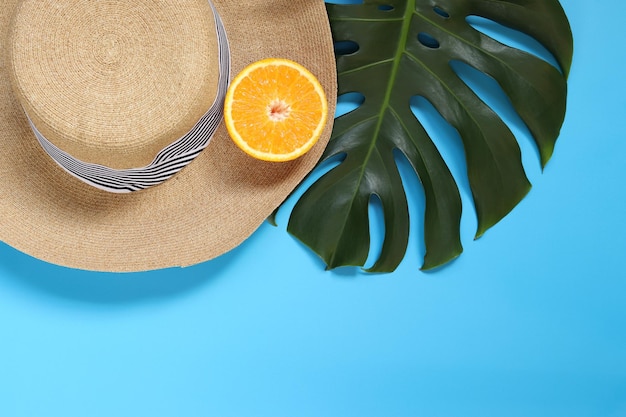 Women's Summer039s chapeau monstera feuille et orange sur un fond bleu espace vide pour le texte