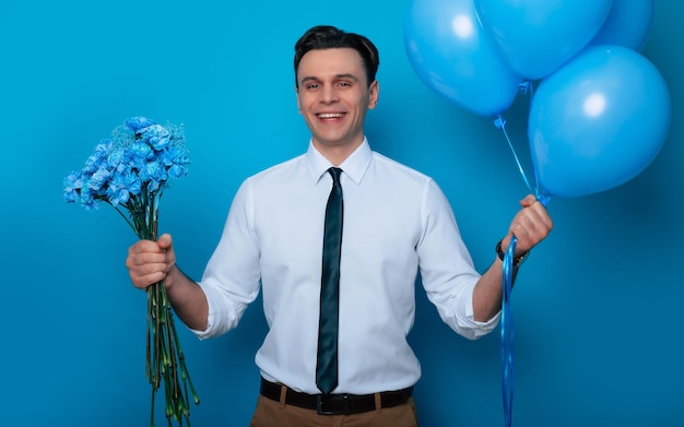 Womens Day Valentines Day Birthday Holidays présente Portrait en gros plan d'un beau mec souriant en chemise et cravate pose avec des ballons et un bouquet de fleurs pour sa femme bien-aimée