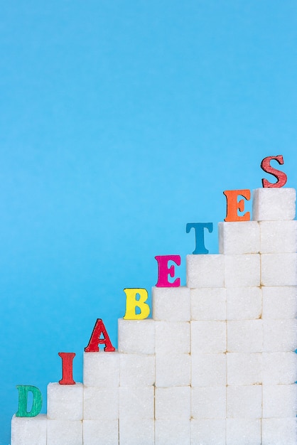 Word diabète sur une échelle de sucre raffiné, fond bleu.