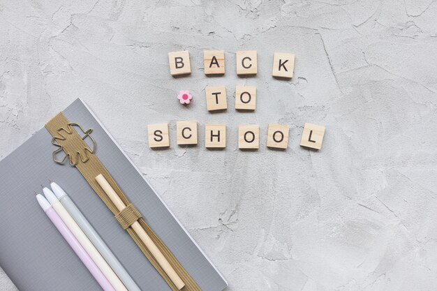 Words BACK TO SCHOOL, cahier et stylos sur gris