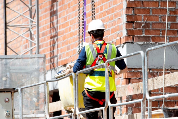 Photo worker in protective and safety equipment directs the lifting of a container with a concrete mixture