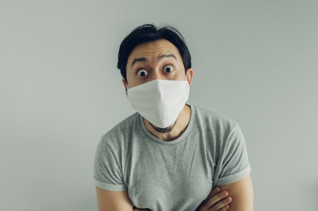 Wow visage d'homme portant un masque hygiénique et un t-shirt gris.