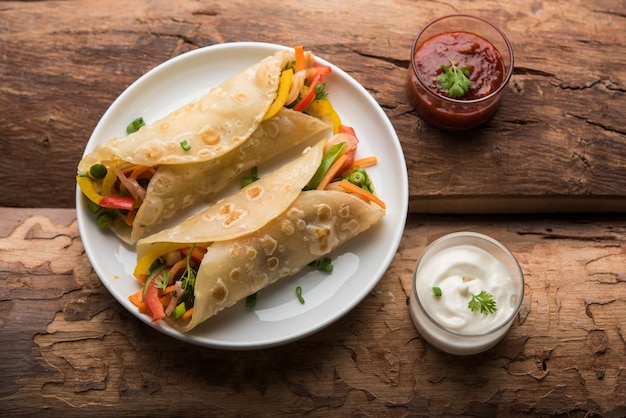 Wrap Chapati Veg indien ou Kathi Roll, servi dans une assiette avec sauce sur fond de mauvaise humeur. mise au point sélective