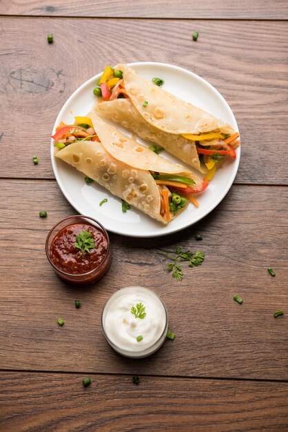 Wrap Chapati Veg indien ou Kathi Roll, servi dans une assiette avec sauce sur fond de mauvaise humeur. mise au point sélective