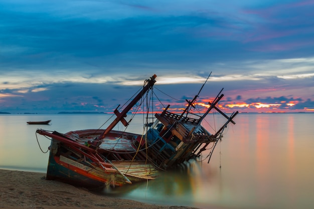 Wreck a été laissé sur la plage avec le beau ciel crépusculaire.