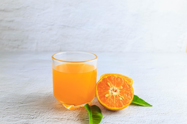 XAFjus d'orange fraîchement pressé dans un verre et agrumes frais sur fond blanc