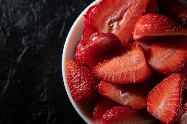 XARed fraises mûres dans une soucoupe sur un gros plan de fond noir