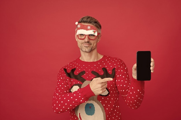 Xmas guy pointer du doigt sur l'écran du téléphone sur fond rouge bonne année