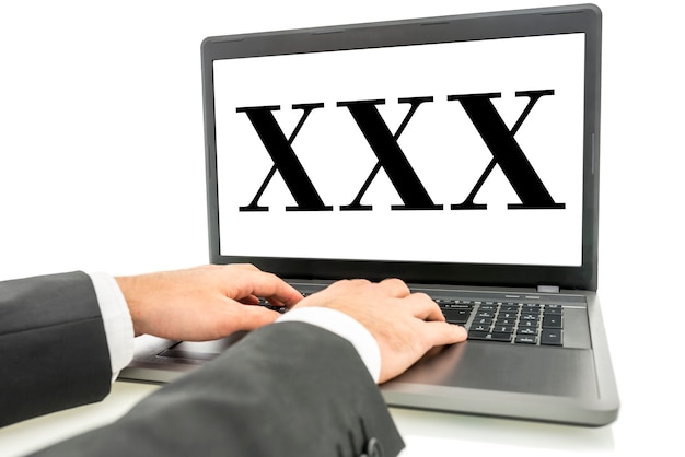 XXX écrit sur un écran d'ordinateur portable sur fond blanc. Notion de porno.