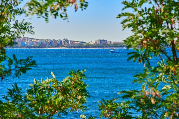 Yacht dans la baie de la mer sur le fond de la ville et un cadre de feuilles