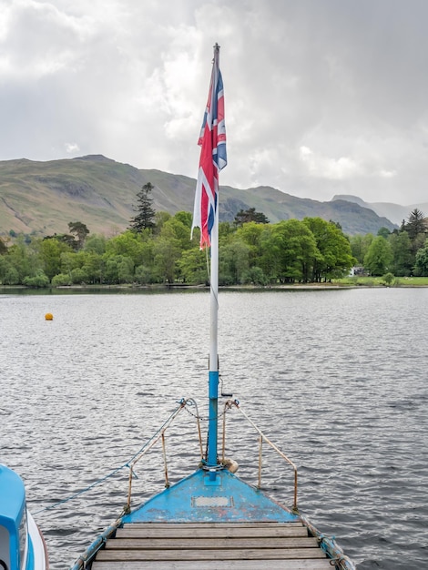 Yacht en jetée rurale dans le lac avec fond de montagne sous un ciel nuageux dans la campagne d'Angleterre