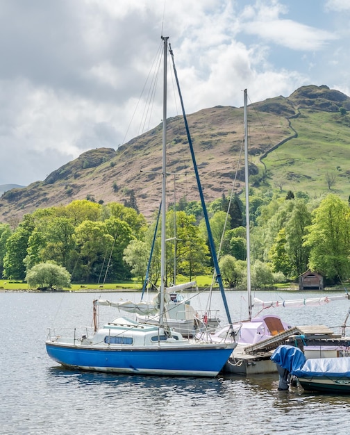 Yacht en jetée rurale dans le lac avec fond de montagne sous un ciel nuageux dans la campagne d'Angleterre