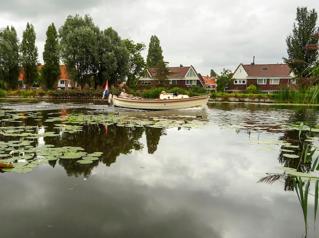 Le yacht navigue le long du canal avec des maisons traditionnelles sur l'eau dans la ville des Pays-Bas