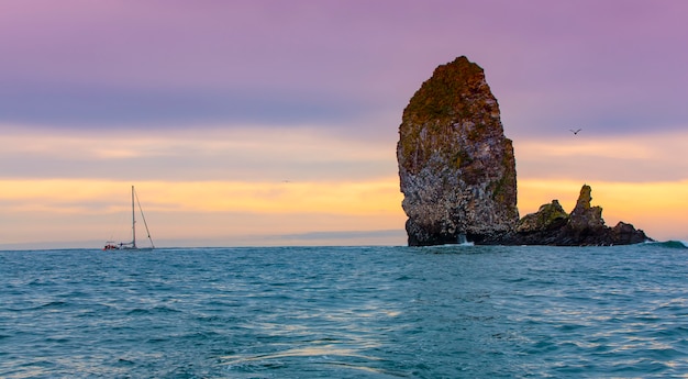 Le yacht près des falaises avec des nids de mouettes dans l'océan Pacifique