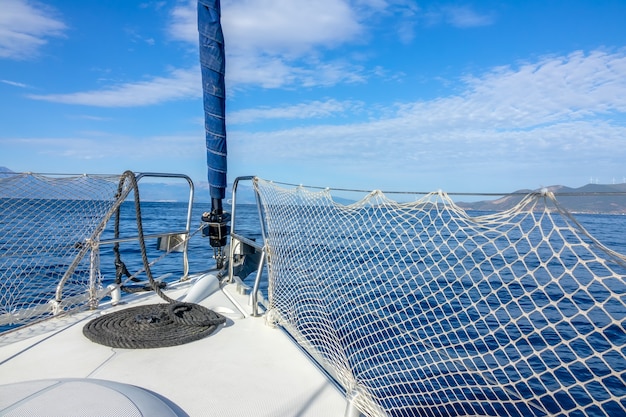 Yacht à voile dans la mer calme. Arc de yacht, cordes et nuages cirrus dans le ciel bleu