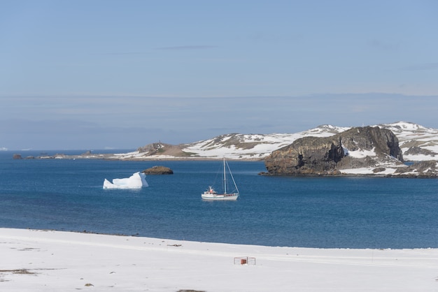 Yacht à voile et iceberg en mer antarctique