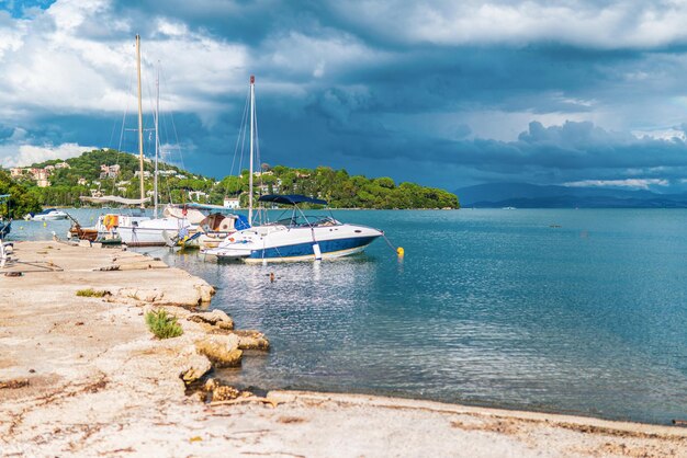 Yachts amarrés à la plage de l'île de Corfou sous un ciel orageux gris
