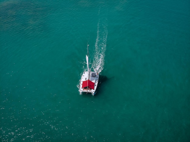 Yachts à voile avec voiles blanches et auvent rouge du soleil pour les passagers en haute mer. Aérien - vue de drone au voilier dans des conditions venteuses