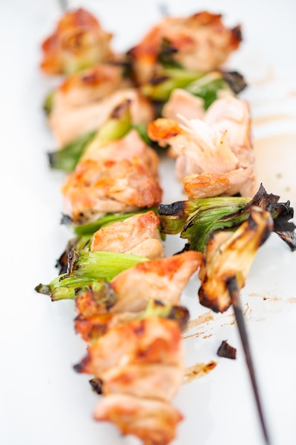 Yakitori de poulet aux oignons verts sur un plateau de service en métal blanc.