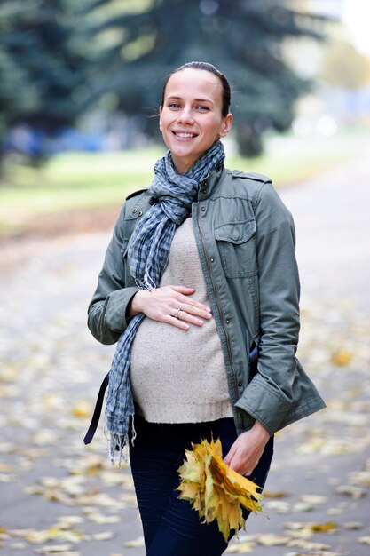 Yang et jolie femme enceinte marche seule sur fond d'automne