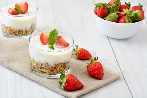 Yaourt aux céréales et fraises sur table en bois blanc