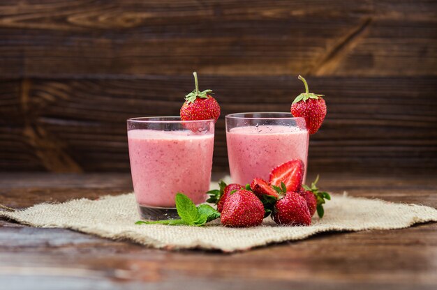 Yaourt aux fraises en bonne santé avec des feuilles de menthe et des baies fraîches sur une vieille table en bois