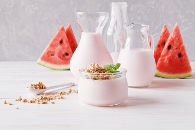 Yaourt aux fruits, smoothies dans un pichet en verre, granola et tranches de melon d&#39;eau