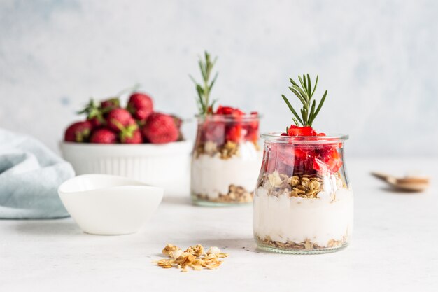 Yaourt Berry avec du yogourt grec, des fraises fraîches et du muesli dans des bocaux. Parfait petit-déjeuner sain dans une tasse en verre