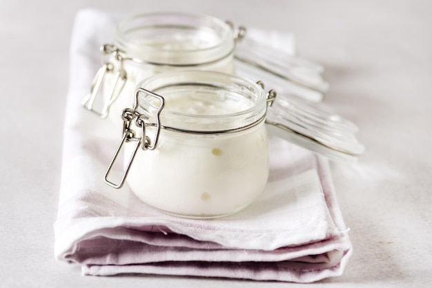 Yaourt dans un bocal en verre sur une serviette en lin Yaourt blanc Petit-déjeuner sain et savoureux Horizontal